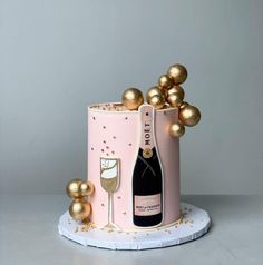 a pink cake with gold decorations and a bottle of champagne