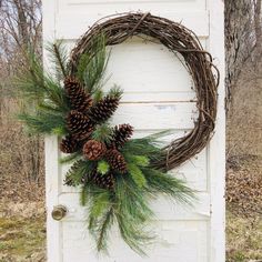 a wreath with pine cones and greenery hangs on the door