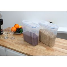 two plastic containers filled with food sitting on top of a counter next to wine glasses