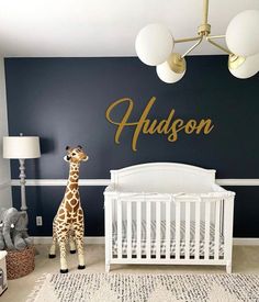 a baby's room with a giraffe statue in the corner and a name sign on the wall