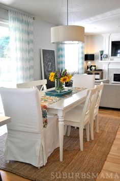 a dining room table with white chairs and yellow flowers