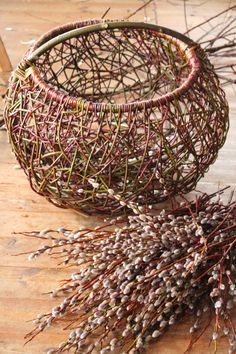 two baskets filled with twigs sitting on top of a wooden table next to each other