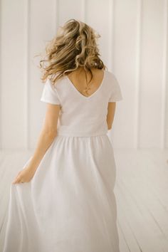 the back of a woman's dress as she walks on a white wooden floor