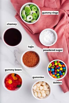 bowls filled with different types of candy on top of a white countertop next to a pink towel