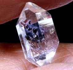 a close up of a person's hand holding a large crystal object in their left hand