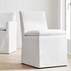 two white chairs sitting next to each other on top of a hard wood floored floor