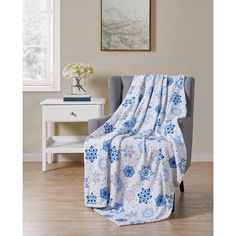 a blue and white blanket sitting on top of a gray chair next to a window