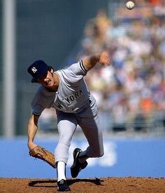 a baseball player pitching a ball on top of a field in front of a crowd