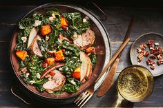 a bowl filled with meat and vegetables next to a glass of wine on top of a wooden table