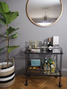 a bar cart with bottles and liquor on it in front of a round mirror