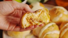 a hand holding up a piece of food in front of some other foods on a plate