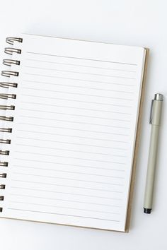 an open notebook and pen on a white surface