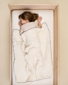 a small child is sleeping in a box with a blanket on it's back