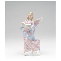 an angel figurine holding a book on top of a white cloud filled ground