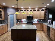 a large kitchen with wooden cabinets and granite counter tops, along with hardwood flooring