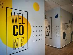 an office hallway with yellow and black graphics on the wall, along with white walls