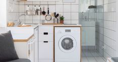 a washer and dryer in a small room with white tiles on the walls