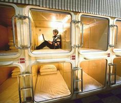 a man sitting on top of a bed in a room filled with bunkbeds