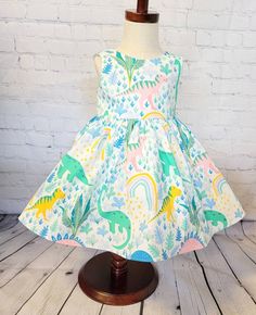 Display dress is a size 3t on a size 3t mannequin. It is shown with tulle petticoat which is NOT INCLUDED in the purchase of this dress. It is for display purposes only. This little pastel dinosaur dress features multi colored dinosaurs in a tropical jungle setting on a cream colored background . It would be perfect for a dinosaur themed birthday party or for any little one that loves dinos! The bodice is lined with soft cotton and it snaps in the back with Kam snaps for easy on and off. There a Cute A-line Dress For Dress-up Occasions, Fitted Princess Summer Dresses, Fitted Princess Sleeveless Dress With Ruffles, Fitted Sleeveless Princess Dress With Ruffles, Cute Green A-line Dress, Summer Fitted Princess Dress, Cute Sleeveless Princess Dress For Garden Party, Playful Fitted Ruffled Princess Dress, Playful Fitted Princess Dress With Ruffles