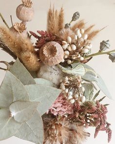 a vase filled with lots of different types of flowers and leaves on top of a table