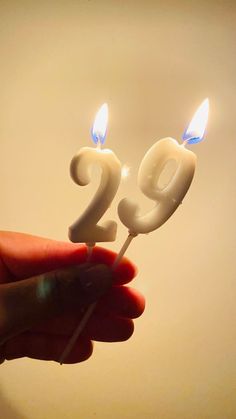 someone is holding two candles in the shape of the number twenty nine on a stick