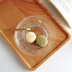 two cookies on a glass plate next to an open book with a spoon in it