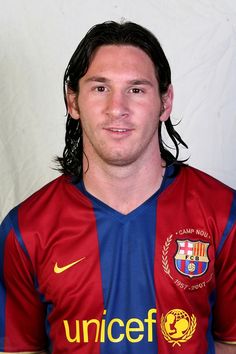 a man with long black hair wearing a red and blue soccer uniform posing for a photo