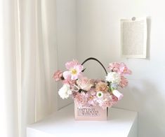 a pink flower basket sitting on top of a white table