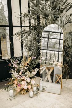 a mirror sitting on top of a table next to a vase filled with flowers and candles