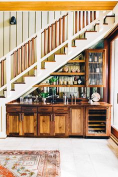 a living room filled with furniture under a stair case next to a wooden table and stairs