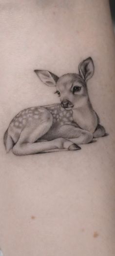 a small deer tattoo on the back of a woman's thigh