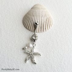 a starfish and pearl belly button ring on a white background with the sea shell in the foreground