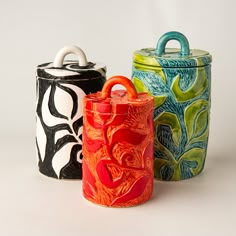 three brightly colored canisters sitting next to each other