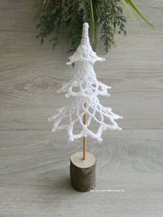 a white crocheted christmas tree sitting on top of a wooden stump