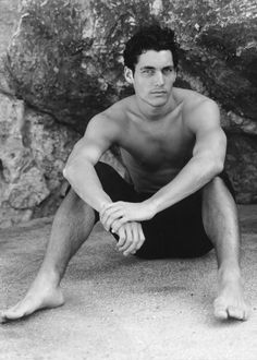 a man sitting on the ground next to a rock