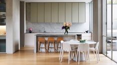 a white table and chairs in a room next to a kitchen with sliding glass doors