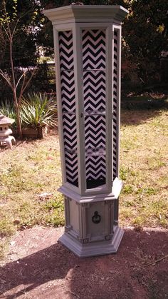 an old grandfather clock sitting in the middle of a yard with grass and trees behind it