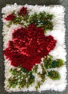 a rug with red flowers and green leaves on top of white shaggyy carpeting