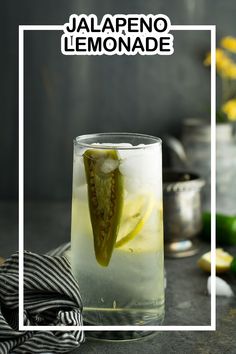 a glass filled with lemonade sitting on top of a table next to limes