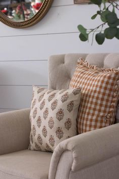 a chair with pillows on it in front of a mirror