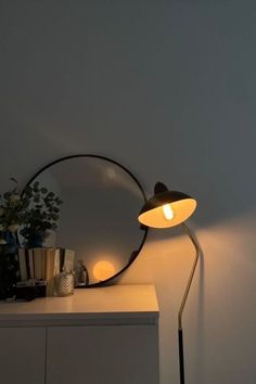 a table lamp sitting on top of a white dresser next to a potted plant