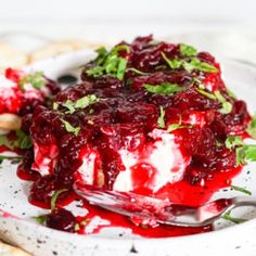 a white plate topped with cranberry sauce and whipped cream next to crackers