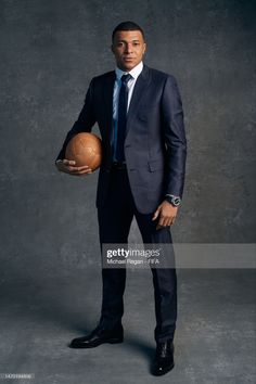 a man in a suit and tie holding a basketball on a gray background stock photo