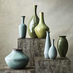 there are many different vases sitting on the wooden stand together in this photo, one is green and the other is blue