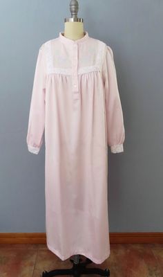 Vintage nightgown from the 80's era!! Pale pink with floral embroidered chest and lace cuffs. Feels like cuddleskin with a satin outside and and soft cotton inside. Button up top bodice. Right hip pocket. This robe is made to stay warm and to cuddle!   Fits a medium-large frame but please double-check the measurements below to ensure the best fit for you.  -- M E A S U R E M E N T S --- Bust: 46" Waist: 50" Hips: 50" Shoulders: 15" Arm Opening: 16" Sleeves: 22" Length: 45" Fabric: Polyester, cotton Label/Era: Gsoftly / 1980 Stated Size: S Condition: Great vintage condition. Freshly laundered. No issues.  ★ Enter the Shop here https://www.etsy.com/shop/RetroSuzysVintage Instagram | retrosuzysvintage Pinterest | retrosuzysvintage Pink Feminine Robe For Sleepover, Feminine Pink Robe For Sleepover, Feminine Long Sleeve Robe For Home, Feminine Long Sleeve Home Robe, Vintage Pink Robe For Loungewear, Feminine Long Sleeve Robe For Daywear, Long Sleeve Pink Nightgown For Spring, Pink Vintage Sleepwear, Long-sleeved Pink Vintage Robe