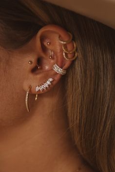 a woman wearing three different types of ear piercings on her left side of the ear