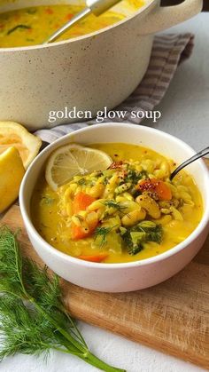 a white bowl filled with soup next to a wooden cutting board and lemon wedges