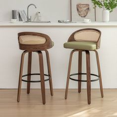 two wooden stools in front of a white counter top with plants on the shelf