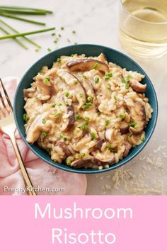 mushroom risotto in a blue bowl next to a fork and glass of water