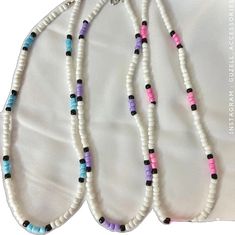 three necklaces with different colored beads are on display in front of a white cloth